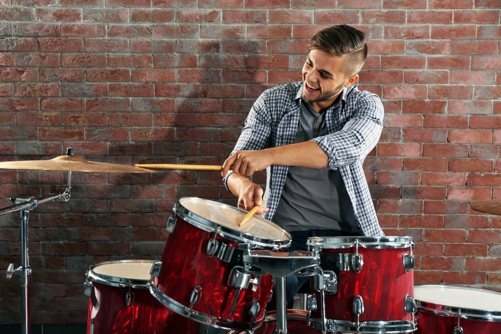 Man playing drums with brick wall in the background